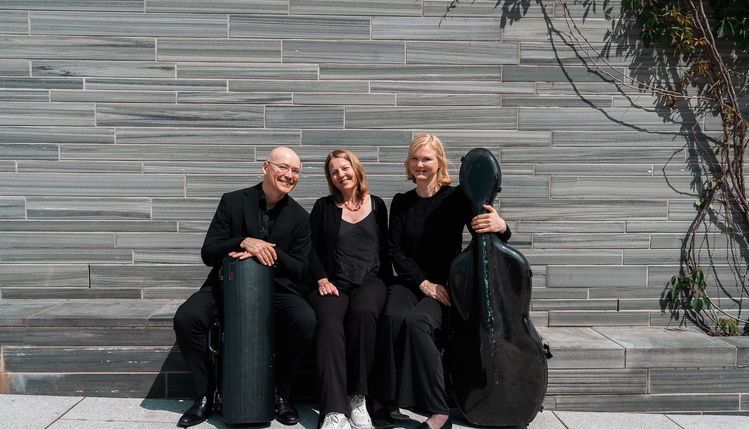 Tre musikere sitter på en steinbenk